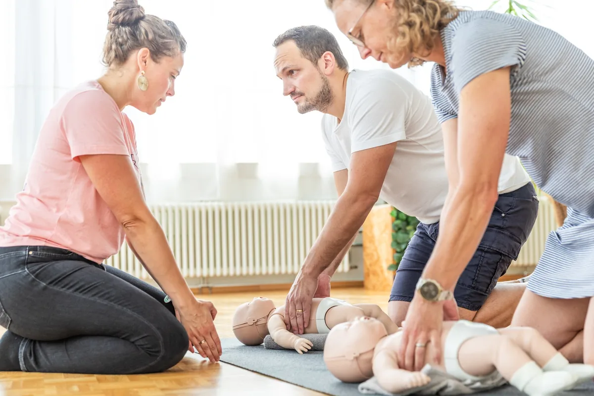 Trois participants s'exercent au massage cardiaque sur des mannequins nourrisson