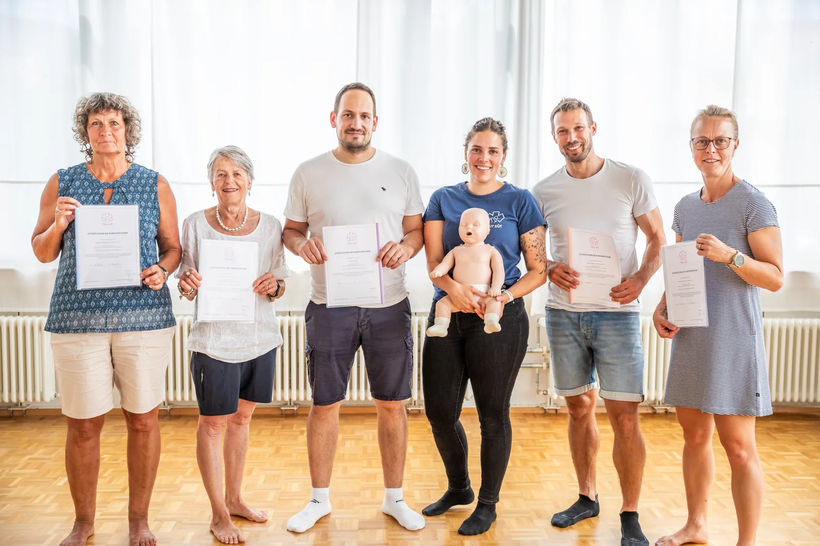 Emilie Grand et les participants d'un cours, debout côte à côte, leur attestation de participation à la main