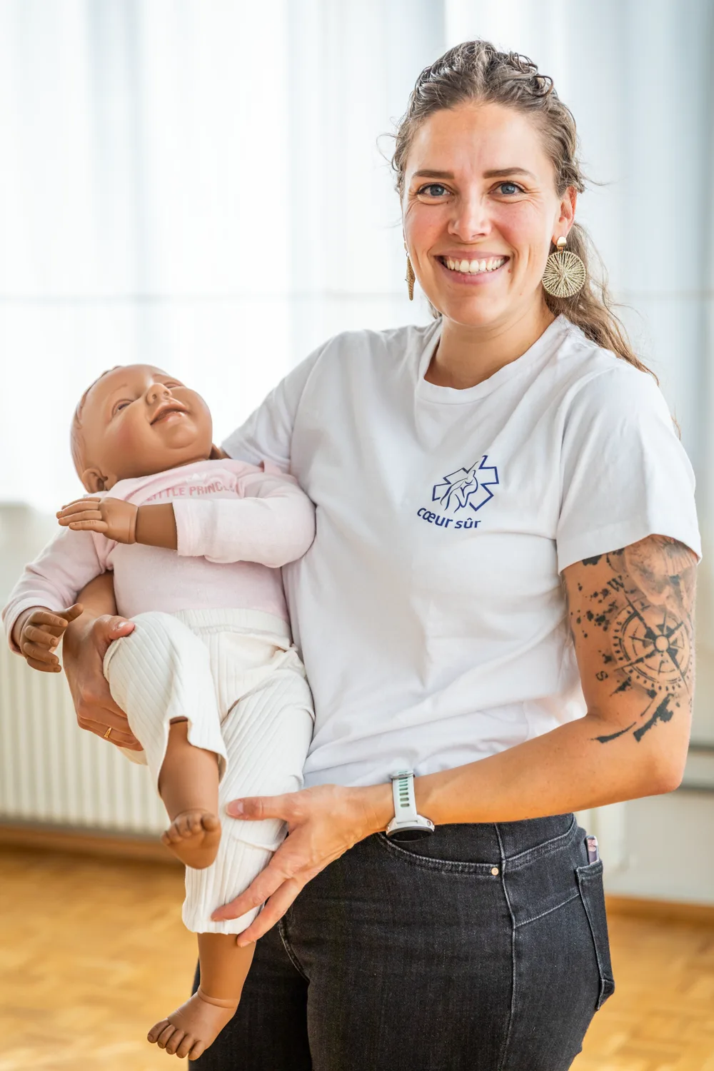 Emilie Grand, ambulancière diplômée ES, tient un mannequin nourrisson dans les bras et sourit
